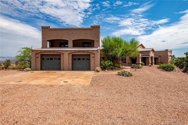 view of front of house with a garage, concrete driveway, and stucco siding