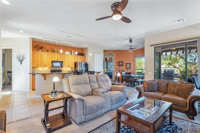 living room with visible vents, ceiling fan, baseboards, and light tile patterned floors