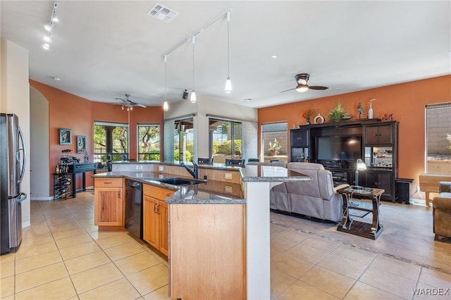 kitchen with black dishwasher, hanging light fixtures, freestanding refrigerator, open floor plan, and dark stone counters