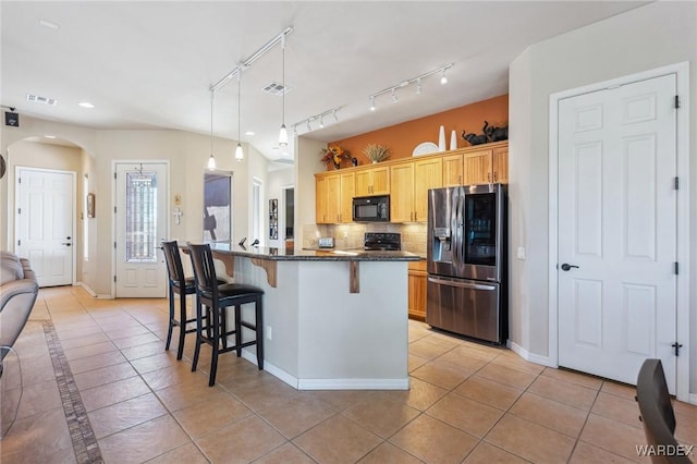 kitchen with stainless steel fridge, a kitchen island, a kitchen breakfast bar, black microwave, and pendant lighting