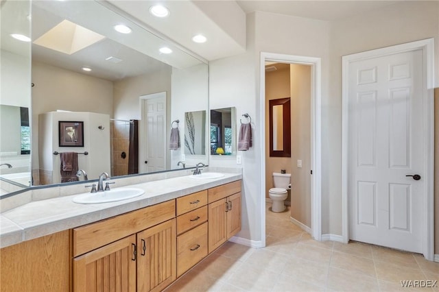 full bathroom featuring a skylight, tile patterned flooring, a sink, and toilet