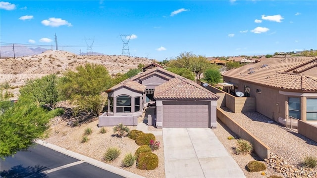 mediterranean / spanish-style house with concrete driveway, a tile roof, an attached garage, and stucco siding