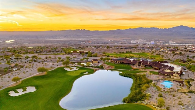 aerial view at dusk with view of golf course, a residential view, and a water and mountain view