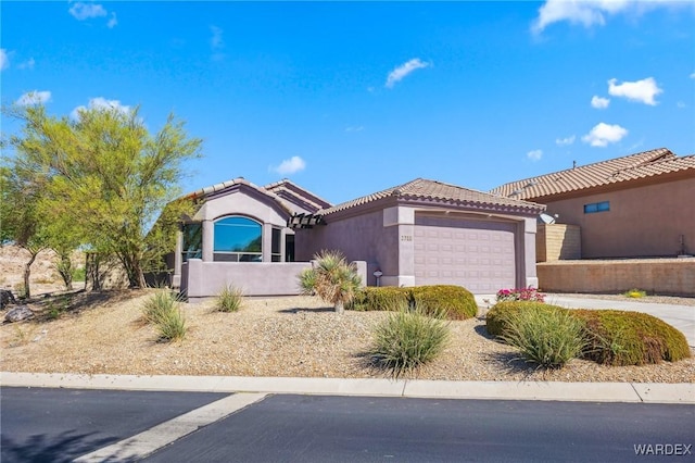 mediterranean / spanish home with a garage, concrete driveway, a tile roof, and stucco siding