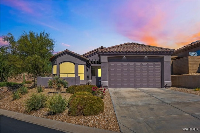 mediterranean / spanish house featuring stucco siding, an attached garage, fence, driveway, and a tiled roof