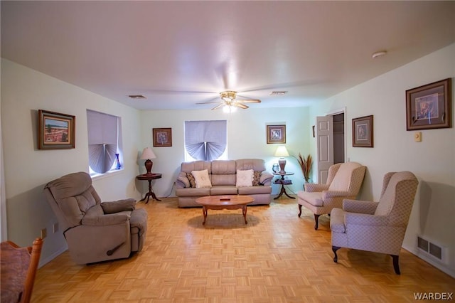 living room with a ceiling fan, visible vents, and baseboards