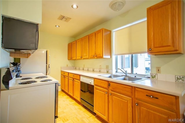 kitchen with white appliances, visible vents, brown cabinetry, light countertops, and a sink