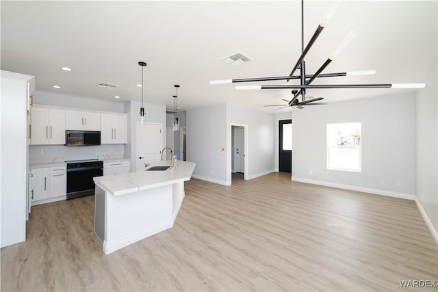 kitchen featuring a center island with sink, visible vents, range, open floor plan, and white cabinetry