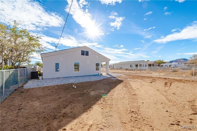 back of house featuring fence, central AC, and stucco siding