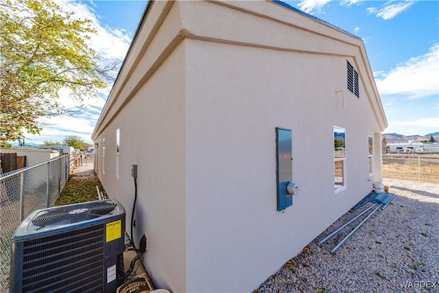 view of property exterior featuring fence, central AC unit, and stucco siding