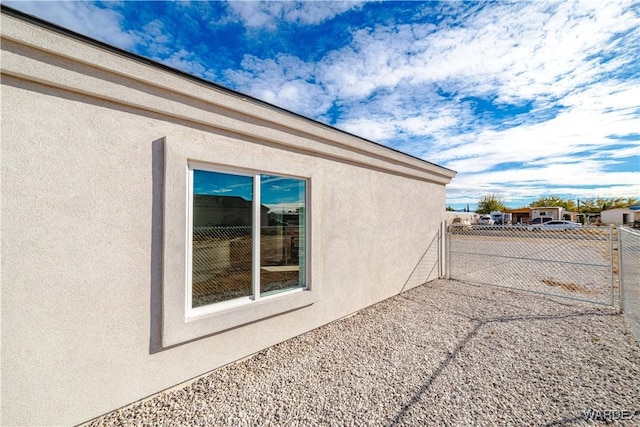 view of side of property with fence and stucco siding