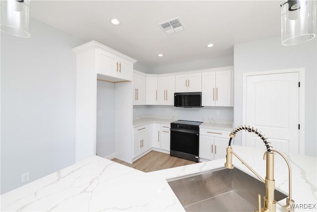 kitchen featuring light stone counters, electric range, a sink, visible vents, and white cabinetry