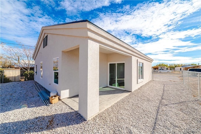 rear view of house with stucco siding, a fenced backyard, and a patio