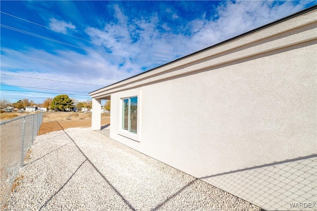 view of side of home featuring fence, a patio, and stucco siding