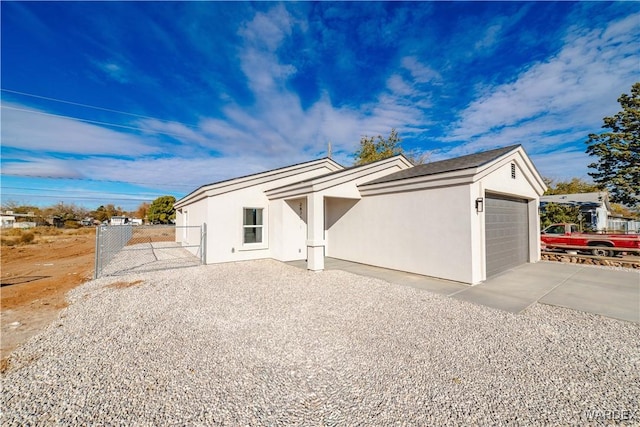 view of front of property featuring an attached garage, driveway, fence, and stucco siding