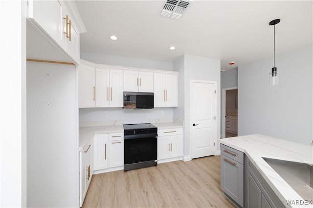 kitchen with decorative light fixtures, visible vents, stainless steel microwave, white cabinetry, and black / electric stove