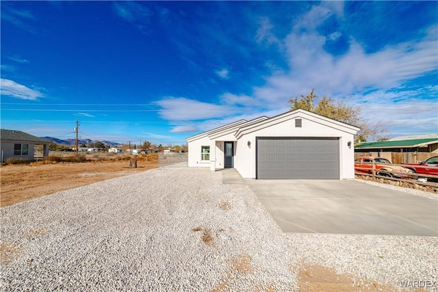 ranch-style house featuring driveway, a garage, and stucco siding