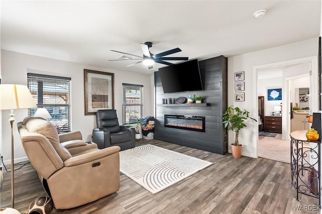 living room featuring a healthy amount of sunlight, a large fireplace, ceiling fan, and wood finished floors