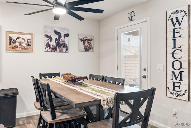 dining space with a ceiling fan, wood finished floors, and baseboards