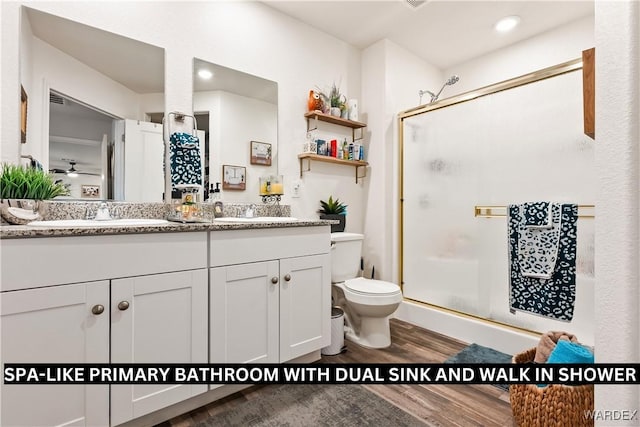 full bathroom featuring double vanity, wood finished floors, a stall shower, and a sink