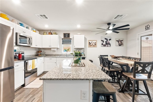 kitchen featuring a breakfast bar, a center island, visible vents, and stainless steel appliances