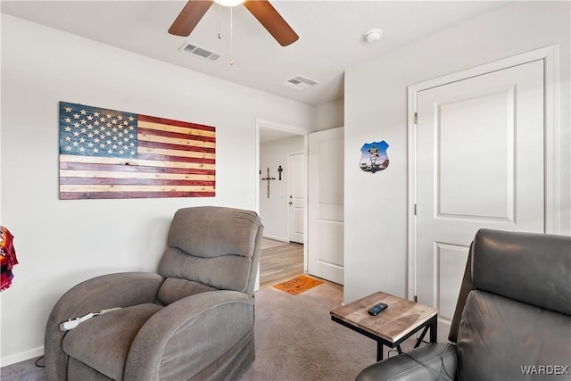 living area featuring visible vents, baseboards, ceiling fan, and carpet floors