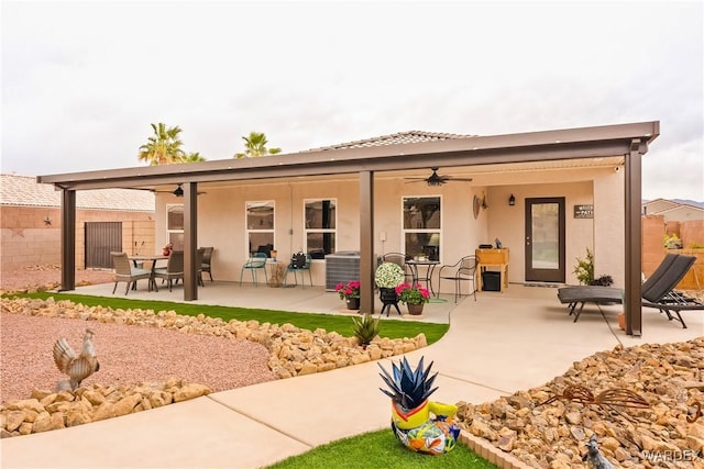 back of property with a patio area, stucco siding, ceiling fan, and fence