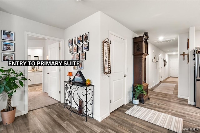 hallway with visible vents, baseboards, and wood finished floors