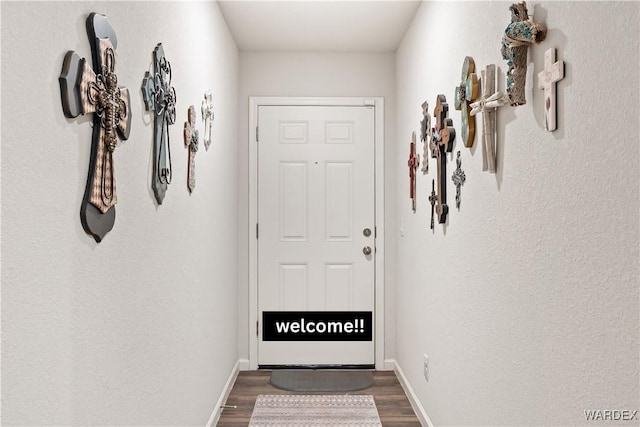 doorway to outside featuring baseboards and wood finished floors