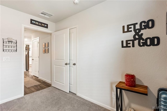 corridor with visible vents, carpet flooring, and baseboards