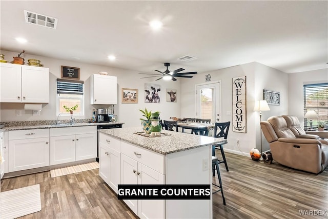 kitchen featuring a kitchen breakfast bar, open floor plan, light wood-style flooring, and visible vents