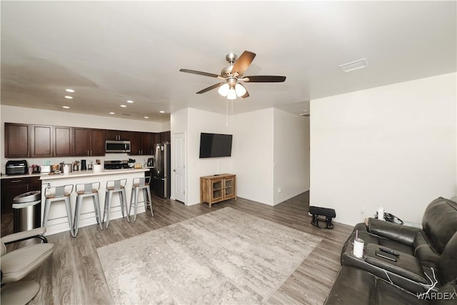 living room featuring ceiling fan, light wood-style flooring, and recessed lighting