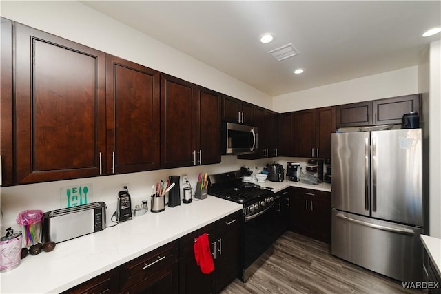 kitchen featuring recessed lighting, wood finished floors, visible vents, light countertops, and appliances with stainless steel finishes