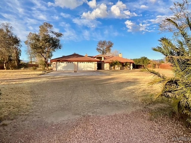 view of front of house featuring driveway, a chimney, an attached garage, and a tiled roof