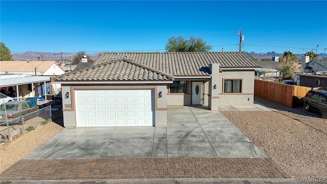 view of front of house with stucco siding, concrete driveway, fence, a garage, and a tiled roof