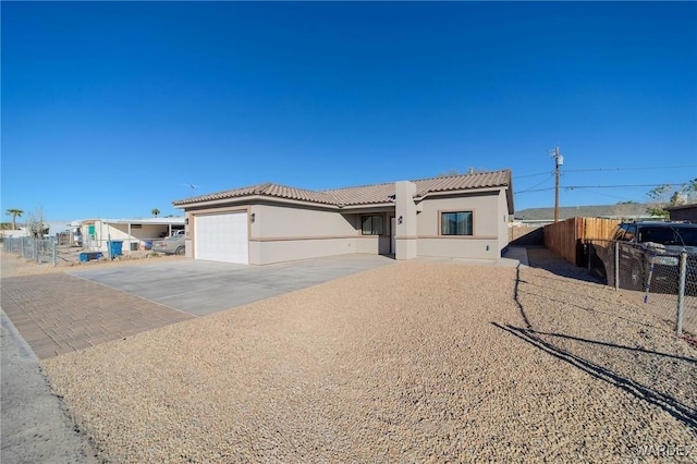 view of front facade featuring a tile roof, stucco siding, concrete driveway, an attached garage, and fence