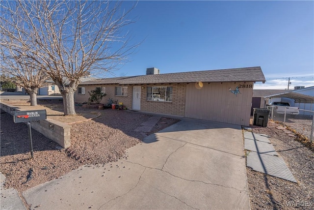 ranch-style house featuring brick siding, fence, driveway, a detached carport, and a chimney