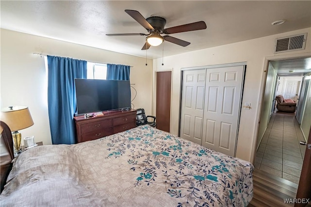 bedroom featuring a ceiling fan, a closet, visible vents, and dark wood-style floors