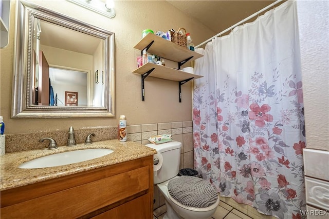 full bathroom with tile walls, toilet, wainscoting, vanity, and tile patterned flooring