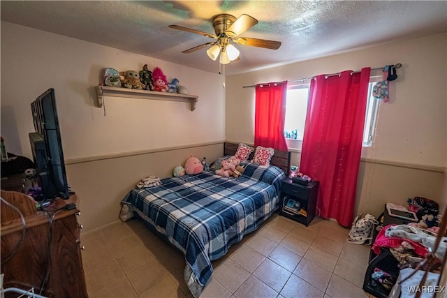 bedroom with a textured ceiling, ceiling fan, and light tile patterned flooring