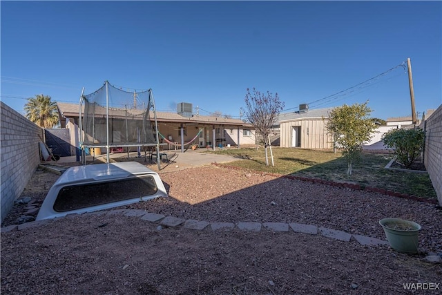 view of yard featuring a trampoline, a patio area, and a fenced backyard