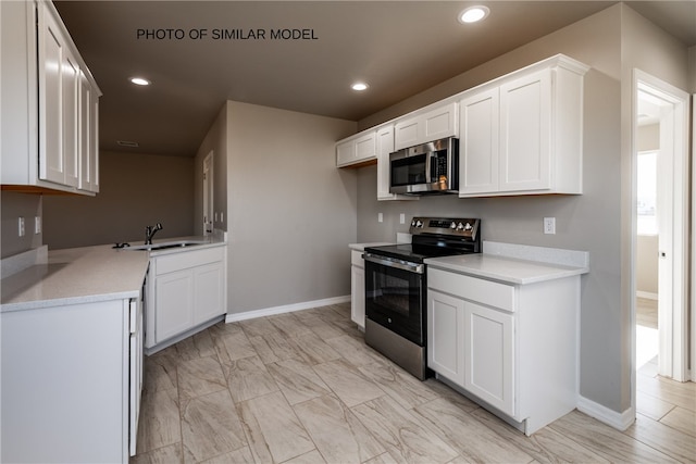 kitchen featuring a sink, recessed lighting, light countertops, white cabinets, and appliances with stainless steel finishes
