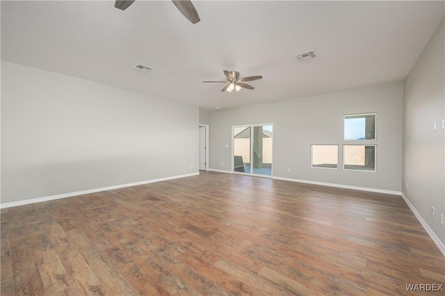 empty room featuring a ceiling fan, baseboards, visible vents, and dark wood-type flooring