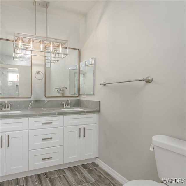 bathroom featuring double vanity, a sink, toilet, and wood tiled floor