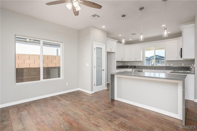 kitchen featuring dark wood-type flooring, a center island, white cabinetry, and visible vents