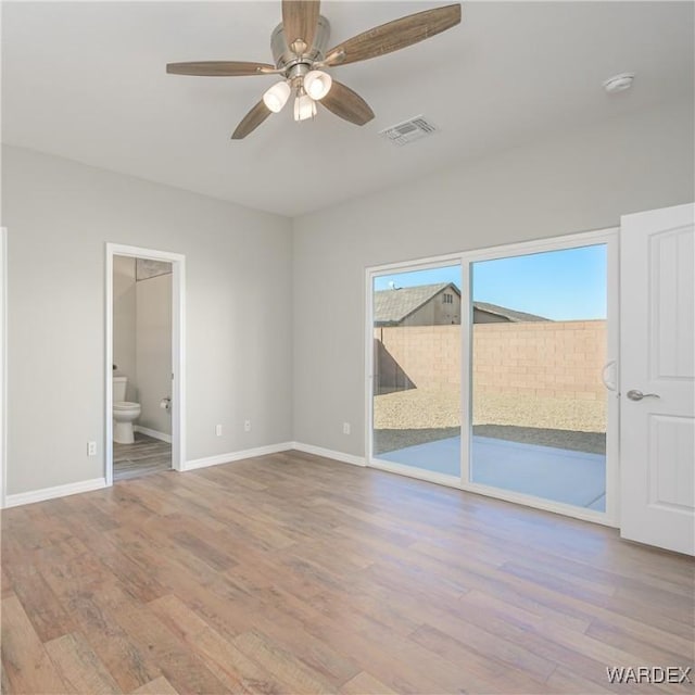 spare room featuring light wood finished floors, a ceiling fan, visible vents, and baseboards