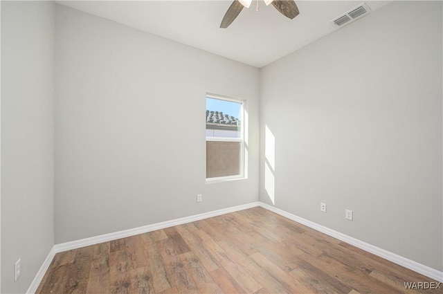 spare room featuring baseboards, visible vents, ceiling fan, and wood finished floors