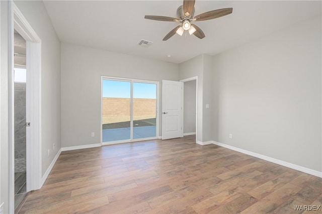 empty room featuring baseboards, visible vents, ceiling fan, and wood finished floors