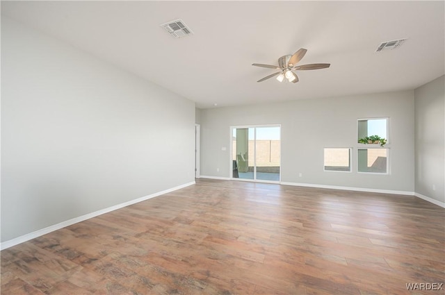 unfurnished room featuring a ceiling fan, baseboards, visible vents, and wood finished floors