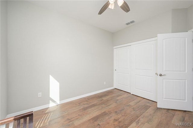 unfurnished bedroom featuring baseboards, visible vents, a ceiling fan, wood finished floors, and a closet